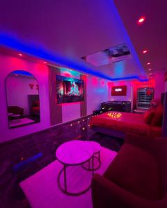 Una habitación con luces violetas y un sofá y una mesa. en Appartement Love Room, jacuzzi spa & sauna, en Chevilly-Larue