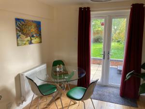 a dining room with a glass table and green chairs at Romantic Country Cottage with Private Hot Tub in Rowde