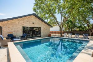 Una piscina con sillas y un edificio. en The Smith Haus - Sleeps 12 Pool Game Room, en Fredericksburg