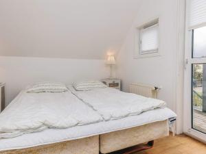 een wit bed in een kamer met een raam bij 5 star holiday home in Løkken in Løkken