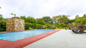 a swimming pool with chairs and a table at Villa El Tucán in Bijagua