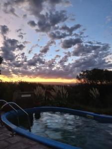 bañera de hidromasaje con puesta de sol en el fondo en Cabaña Las liebres, en San Roque