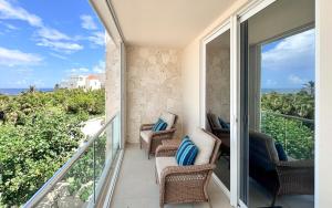 a balcony with chairs and a view of the ocean at Tortuga Azul Private Terrace Rooftop Pool W BBQ Beach Access 11 Pools Free Beach Club in Akumal