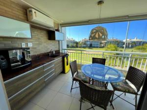 a kitchen with a table and chairs and a balcony at Golf Ville Resorts Residence 3 Suítes, Porto das Dunas in Aquiraz