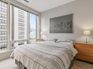a bedroom with a large bed and large windows at Cozy Condo in the heart of the city in Vancouver