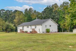 a white barn in a field with trees in the background at 8 Mi to Jordan Lake Spacious New Hill Home in Apex