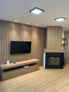 a living room with a fireplace and a flat screen tv at Apartamento Bolognese in Canela
