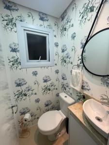 a bathroom with a toilet and a sink and a mirror at Apartamento Bolognese in Canela