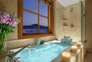 a bathroom with a tub with candles and a window at Snake River Lodge in Teton Village +66 photos