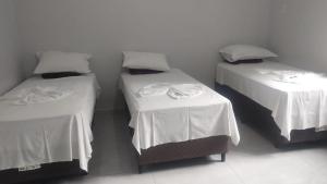 a room with two beds with white sheets at Pousada Solar das Águas 