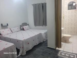 a bedroom with two beds and a bathroom with a toilet at Pousada do Sossego Mar e verde 3 in Itanhaém +94 photos