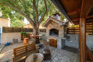 Un patio con chimenea de piedra y un árbol. en Holiday house with a swimming pool Konjevrate, Krka - 24925, en Konjevrate