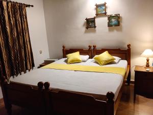 a bedroom with a bed with yellow pillows at Mansion Du Lac in Kottayam