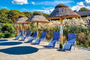 un gruppo di sedie e ombrelloni su un patio di Comfortable holiday homes with a pool a Ustronie Morskie