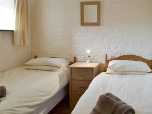 a bedroom with two beds and a night stand with a lamp at Nightingale Cottage- 25115 in Flamborough