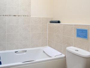 a bathroom with a white tub and a toilet at Nightingale Cottage- 25115 in Flamborough