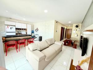 un salon avec un canapé blanc et une cuisine dans l'établissement Seu Refúgio em carneiros 3 Quartos C Ar, piscina privativa, à Tamandaré