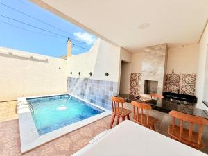 une piscine dans une pièce avec une table et des chaises dans l'établissement Seu Refúgio em carneiros 3 Quartos C Ar, piscina privativa, à Tamandaré