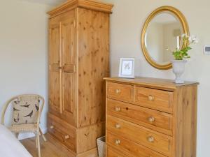 a bedroom with a wooden dresser and a mirror at The Peacock Barn in Burwash