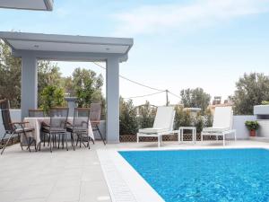 ファリラキにある2-Bedroom Villa with Private Pool in Kalithiesのスイミングプールのそばにパティオ(テーブル、椅子付)