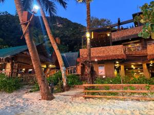 a resort on the beach with palm trees and a building at Tagosilangan Beach House in Buruanga