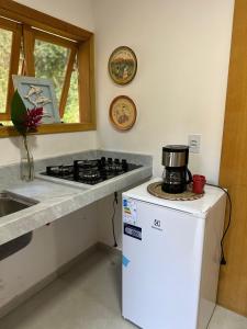 a kitchen with a stove and a white refrigerator at Suíte 5 Vila dos Pescadores Cond Portogalo in Angra dos Reis