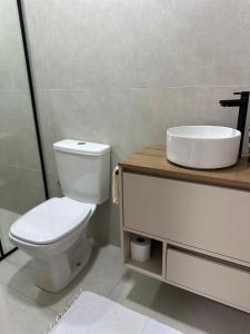 a bathroom with a white toilet and a sink at Suíte 5 Vila dos Pescadores Cond Portogalo in Angra dos Reis