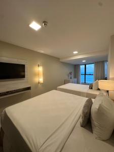 a hotel room with two beds and a flat screen tv at Seaside Refuge in Recife
