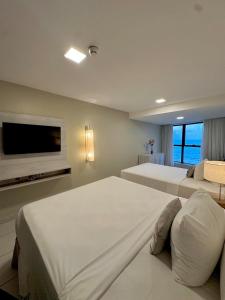 a bedroom with two beds and a flat screen tv at Seaside Refuge in Recife
