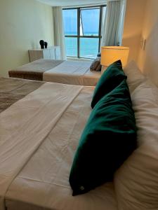 two beds with green pillows on them in a bedroom at Seaside Refuge in Recife