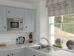 Una cocina blanca con fregadero y ventana. en Charborough House Apt 3, en Salcombe