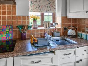 a kitchen sink with a dish drying rack next to it at Ikkle Cottage in Blidworth