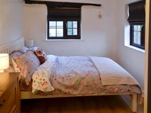 a bedroom with a bed with a blanket and a window at Ikkle Cottage in Blidworth