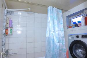 a shower curtain in a bathroom with a washing machine at JOMIY Guest House in Margilan