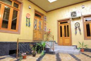a yellow house with wooden doors and flowers on it at JOMIY Guest House in Margilan +33 photos