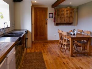 a kitchen with a wooden table and a wooden floor at Mullins Cottage in Gristhorpe