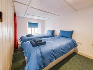 2 Betten in einem Zimmer mit blauer Bettwäsche in der Unterkunft Riverside Cottage in Lynton + 7 Fotos