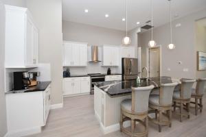 a kitchen with white cabinets and a kitchen island with bar chairs at Modern 3BR Retreat Heated Pool & Large Game Room in Bunnell