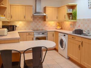 Una cocina con muebles de madera y lavadora. en Seahaven Cottage, en Portknockie