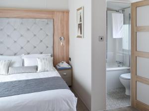 1 dormitorio con cama, bañera y aseo en Reel Paradise - Uk37723, en Ingoldmells 2 fotos más