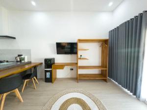 a room with a table and a desk and a television at Terramar Villas in Kuta Lombok
