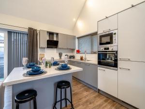 a kitchen with white cabinets and a counter with stools at Ferndale Bungalow in Hambleton