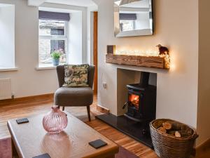 ein Wohnzimmer mit Kamin und Sessel in der Unterkunft Ivy Cottage in Dent