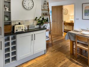 a kitchen with a table and a clock on the wall at The Lodge in Fowey