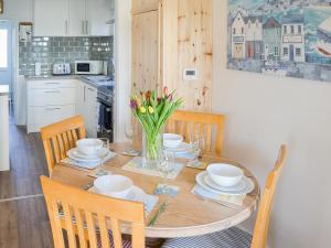 un tavolo da pranzo con un vaso di fiori sopra di Cottage By The Sea a Bacton
