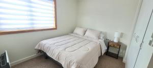 Un dormitorio blanco con una cama con ventana. en Refugio Oriente, en Osorno