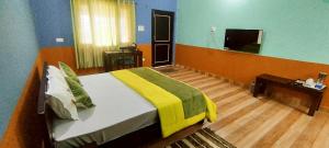 a bedroom with a large bed with a yellow and green blanket at Aasara Homestay Bhimtal in Bhīm Tāl