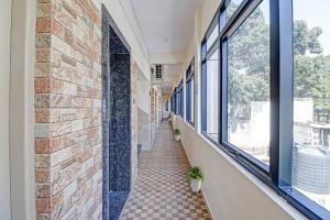TumkūrにあるHotel O I Care With Greenery Comfortsの窓のあるタイルフロアの建物廊下