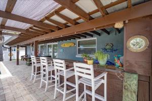 a patio with a bar with white bar stools at Waterfront Retreat with Pool Tiki Bar & Boat Dock in Bon Terra