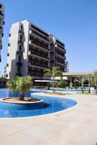 a large building with a palm tree in front of it at Apartamento moderno com uma ótima área de lazer in Brasilia